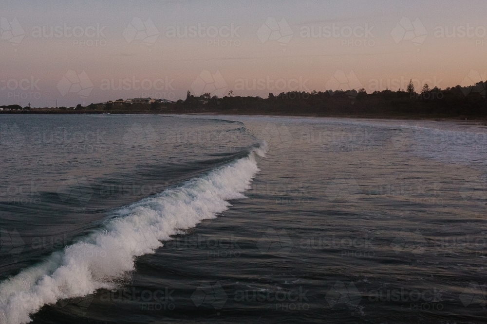 sea with waves and a silhouette shoreline in the background - Australian Stock Image