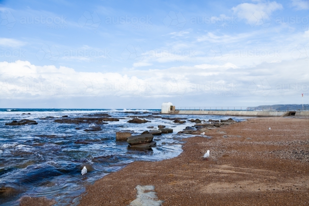 Seaside scene at Merewether looking along beach to the ocean and pumphouse - Australian Stock Image