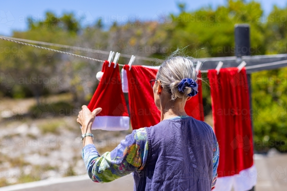 seen from behind lady hanging out santa suit on a clothesline - Australian Stock Image