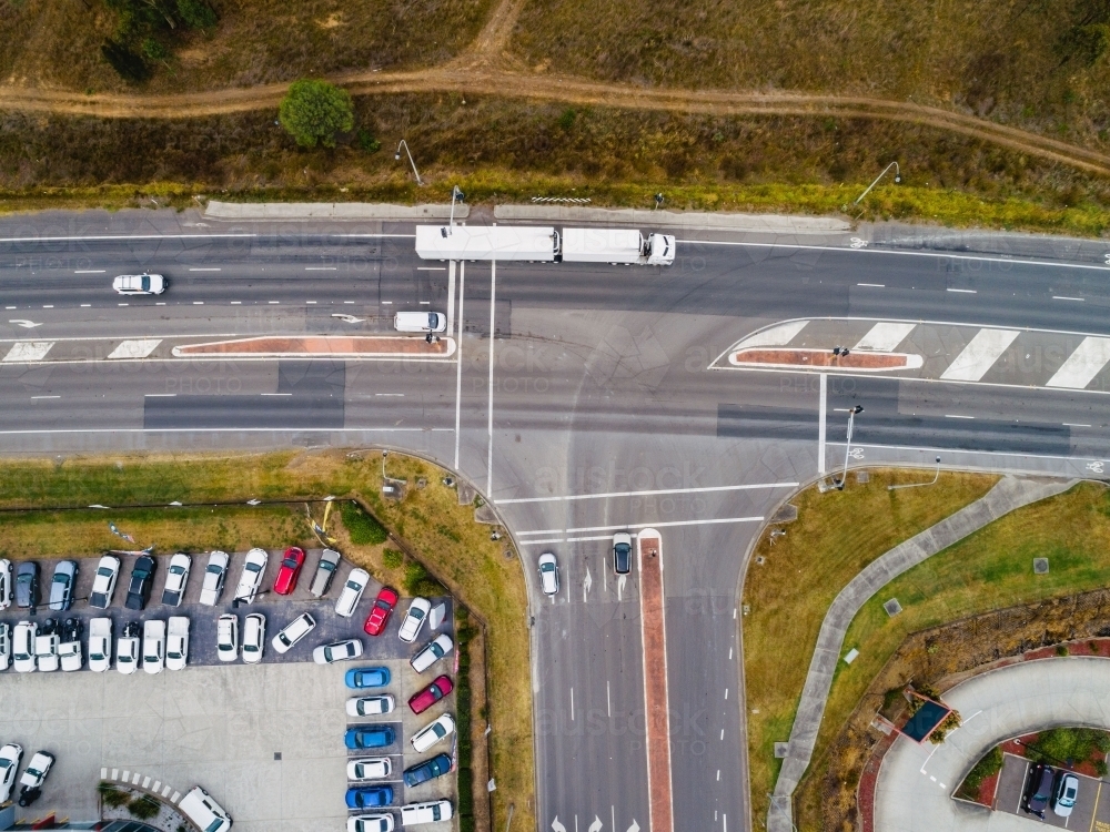 semi trailer truck going through intersection beside car yard dealership - Australian Stock Image