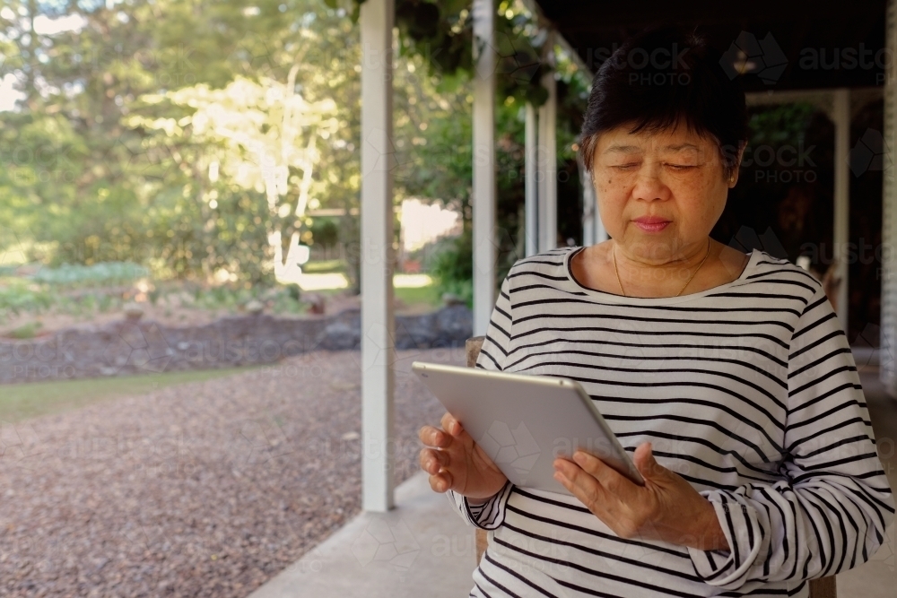 Senior Asian woman using tablet - Australian Stock Image