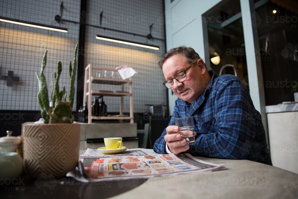 Senior Man Reading Newspaper in Coffee Shop - Australian Stock Image