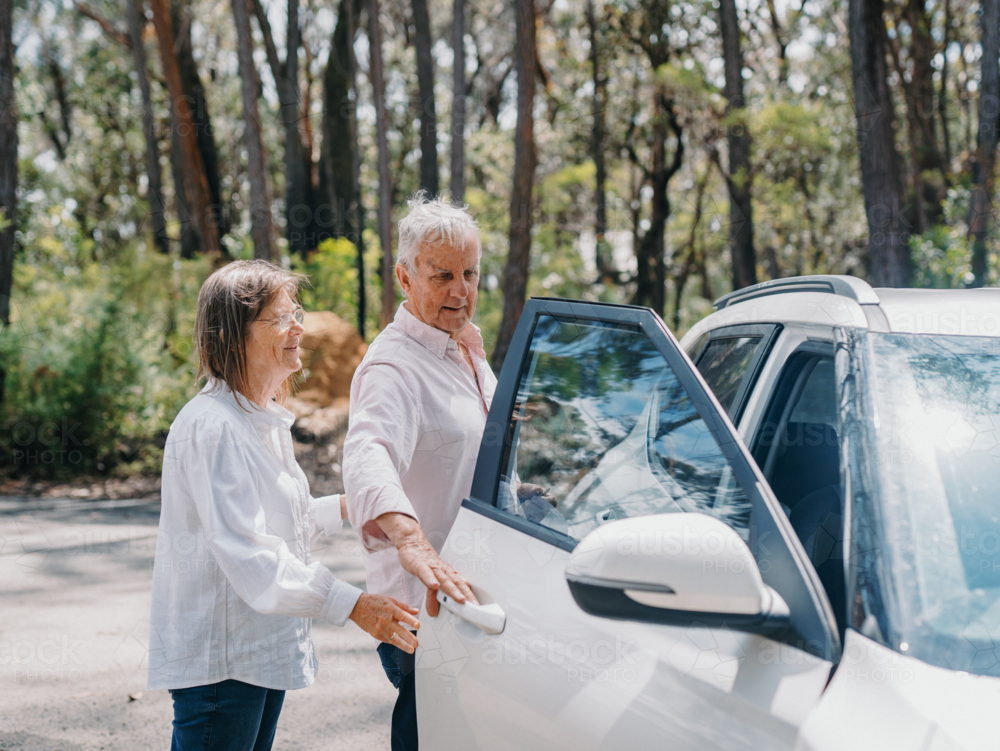 senior retiree couple opening car door in bushland parking space - Australian Stock Image