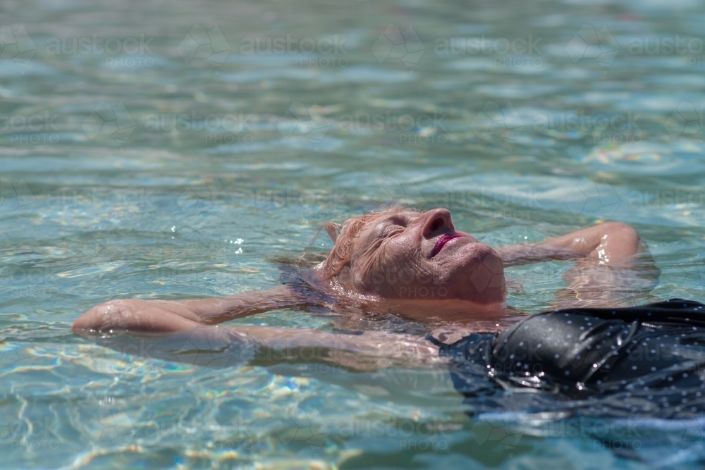 senior woman floating in water - Australian Stock Image