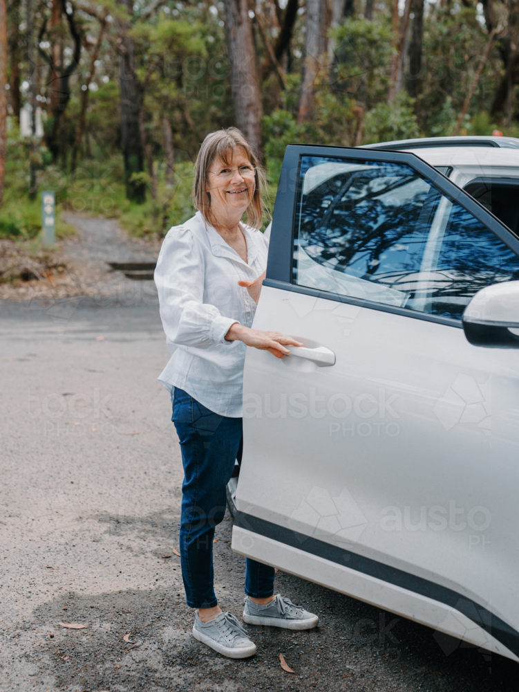 senior woman opening car door in Australian bushland - Australian Stock Image