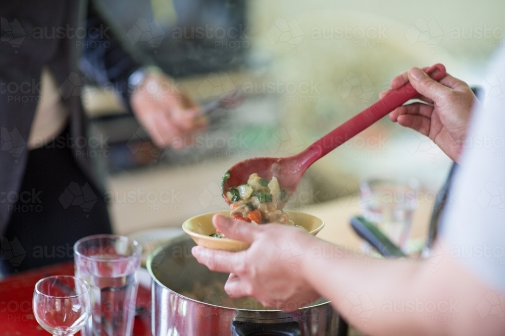 Serving steaming food into a bowl - Australian Stock Image