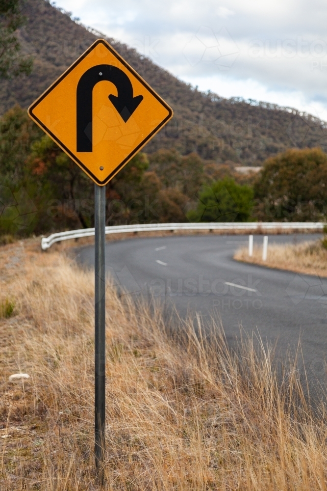 Sharp bend, turn in road sign on mountain road - Australian Stock Image