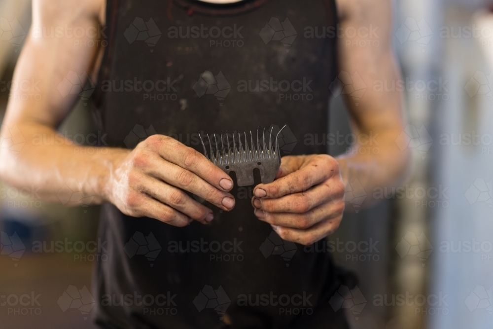 shearer holding shearing comb in dirty hands - Australian Stock Image