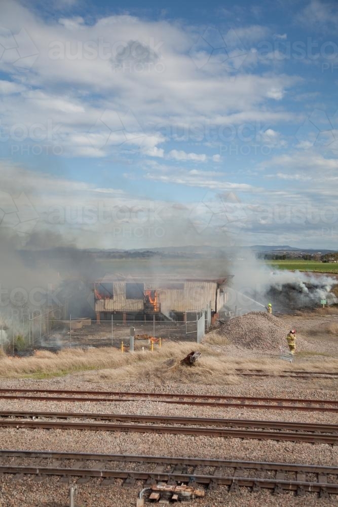 Shed burning down and firefighters putting out the flames - Australian Stock Image