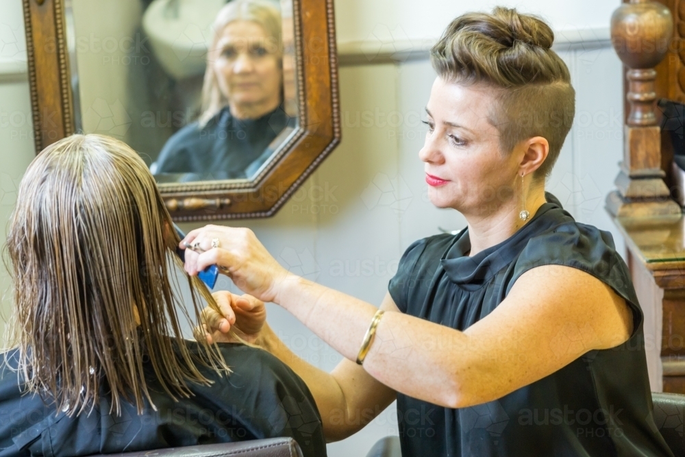 Side on view of a hairdressing cutting a ladies hair - Australian Stock Image