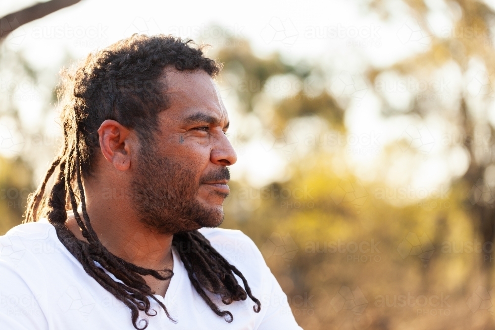 Side profile of Aboriginal Australian man looking off into bushland - Australian Stock Image