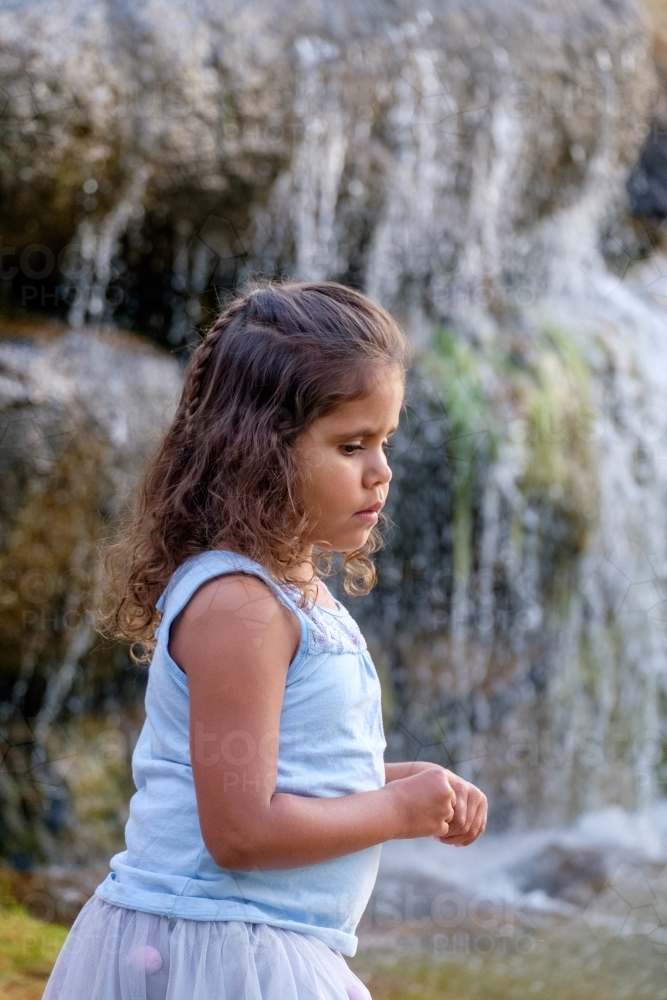 Side profile of an eight year old girl with waterfall in the background - Australian Stock Image