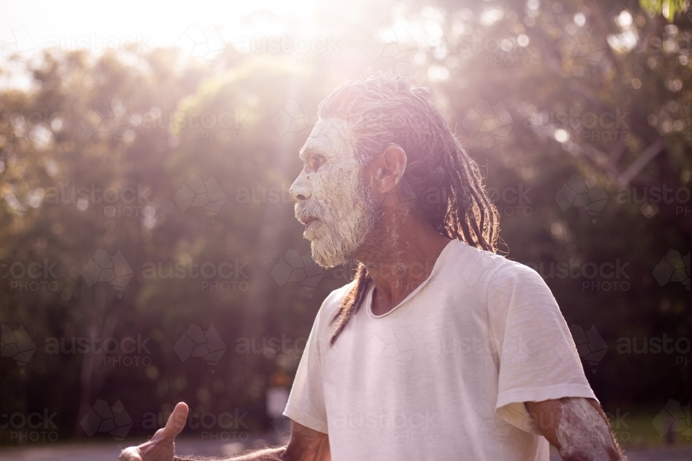 Side profile portrait of aboriginal man with sun flare - Australian Stock Image