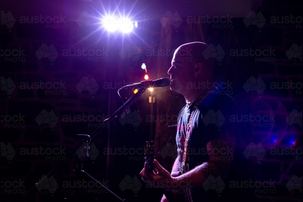 Side view of rock singer and reflection performing and lit with pink light - Australian Stock Image