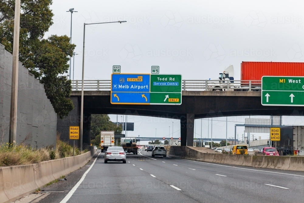 Sign to Melbourne airport and toll road with roadwork ahead warning - Australian Stock Image