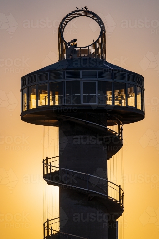 Silhouette of a modern lookout tower against a golden dawn sky - Australian Stock Image