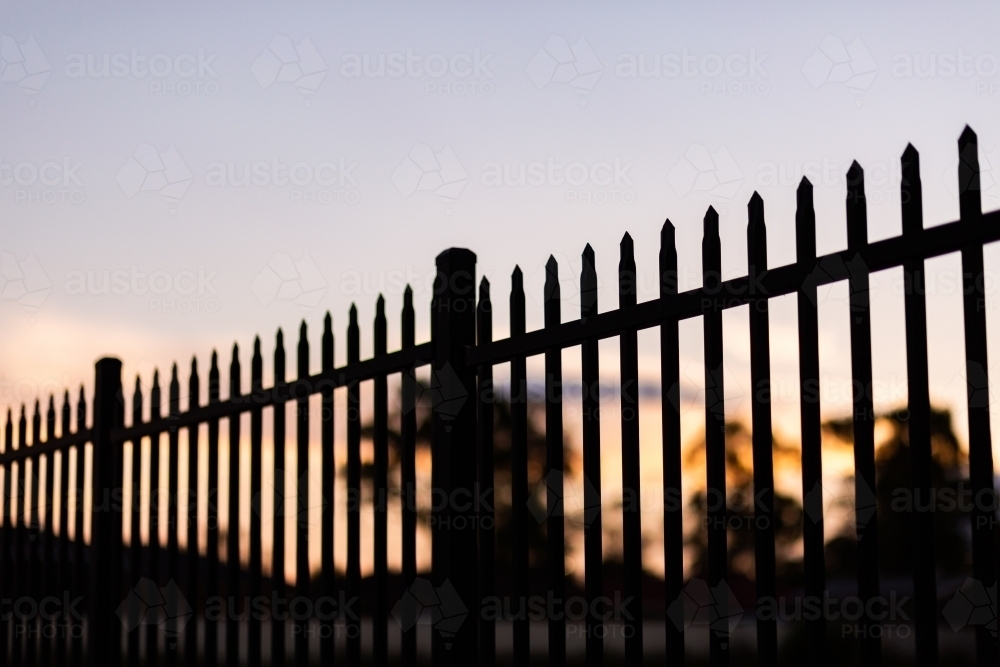 Silhouette of a pointed school fence at sunset - Australian Stock Image