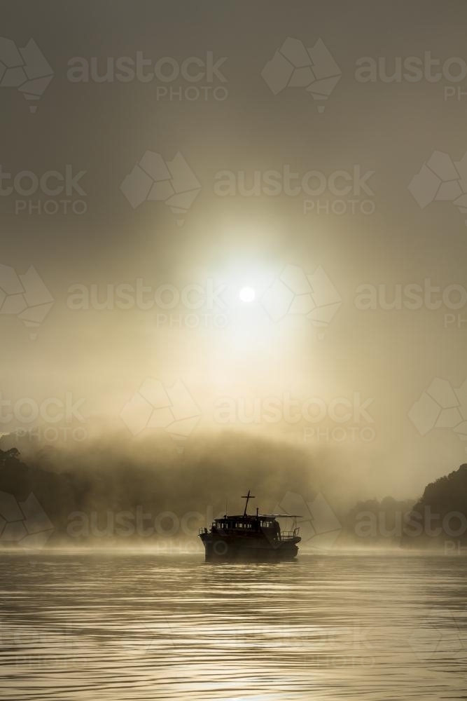 Silhouette of old wooden boat on the water in fog - Australian Stock Image