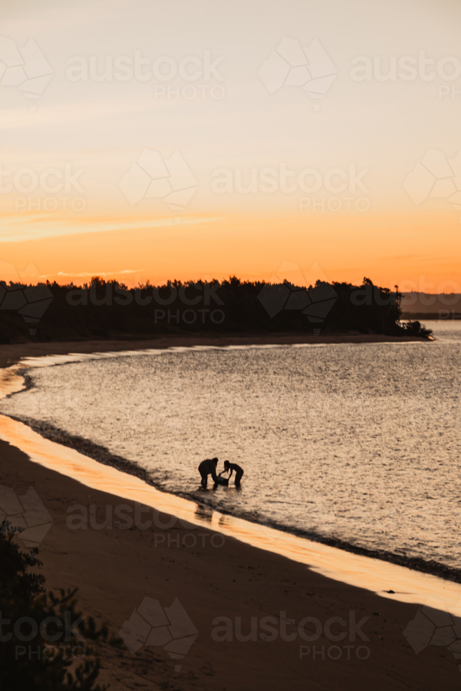 Silhouette of people enjoying Whiting Beach at Yamba at sunset - Australian Stock Image