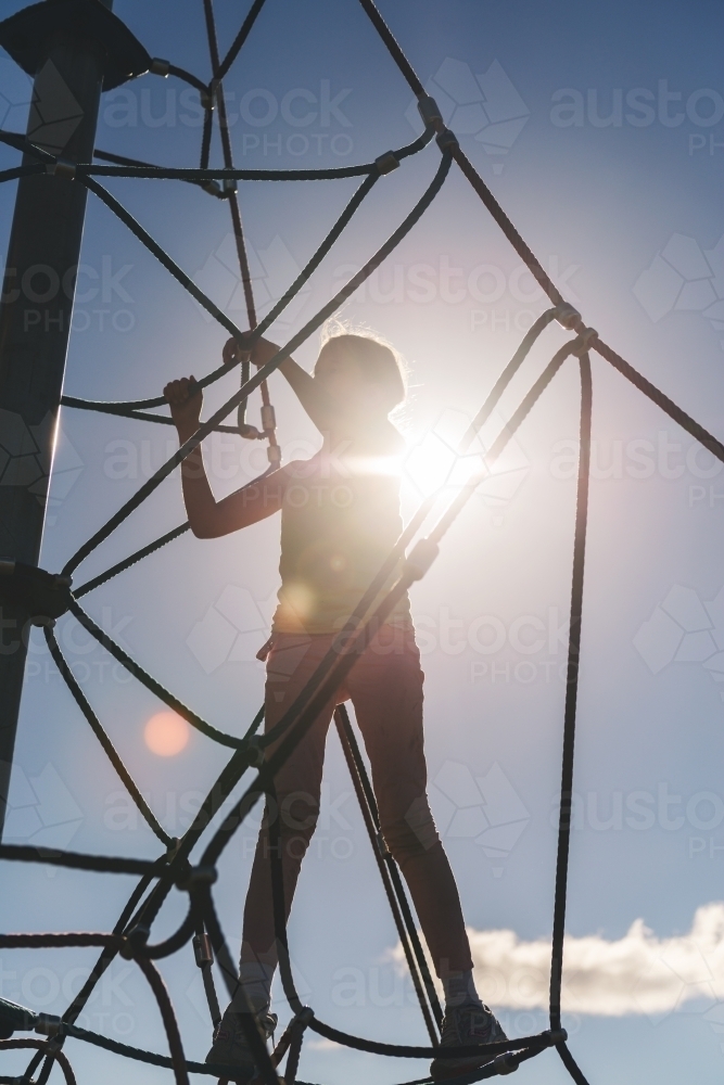 silhouette of tween girl on jungle gym - Australian Stock Image