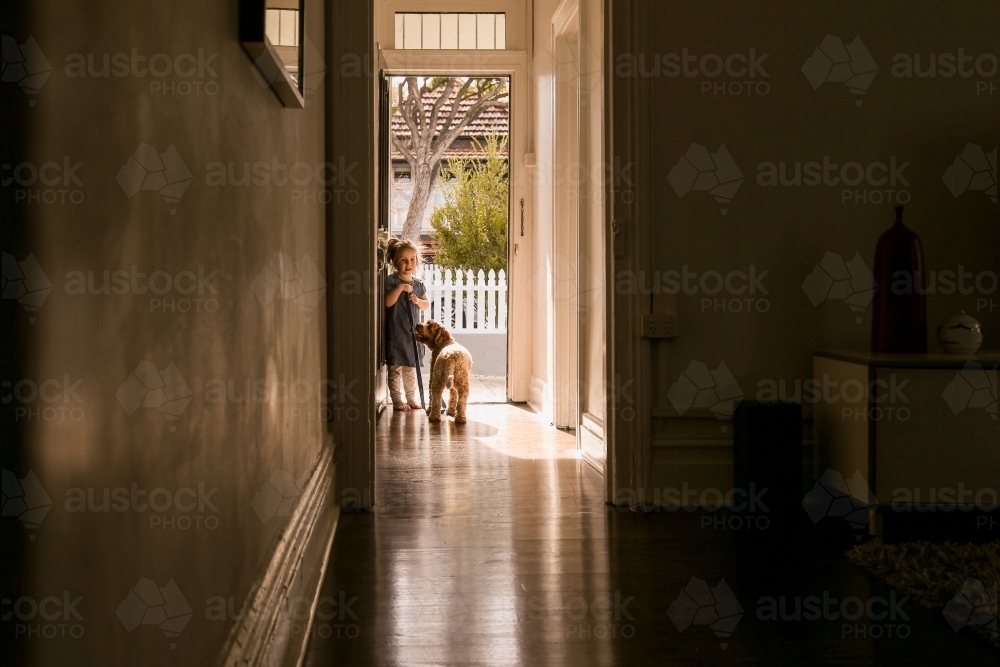 silhouette shot of a little girl with a dog on a leash in the corridor - Australian Stock Image