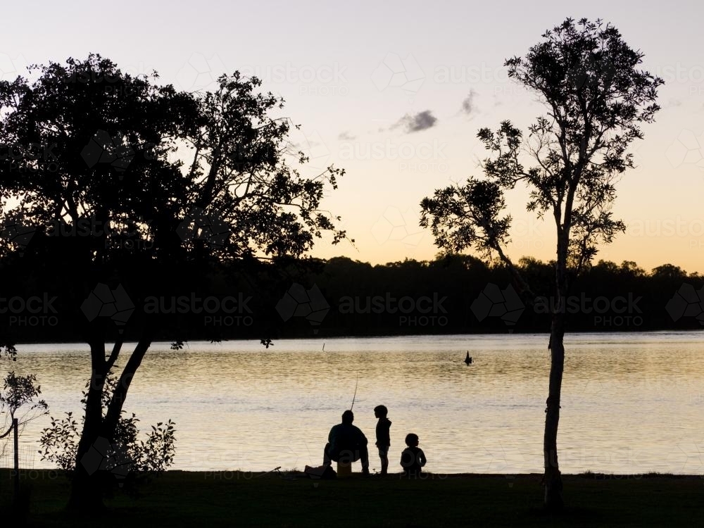 Silhouetted father and two son fishing - Australian Stock Image