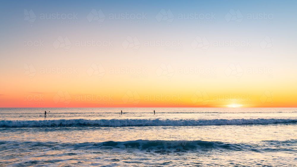 Silhouettes of people paddleboarding at Southport beach in Port Noarlunga, South Australia - Australian Stock Image