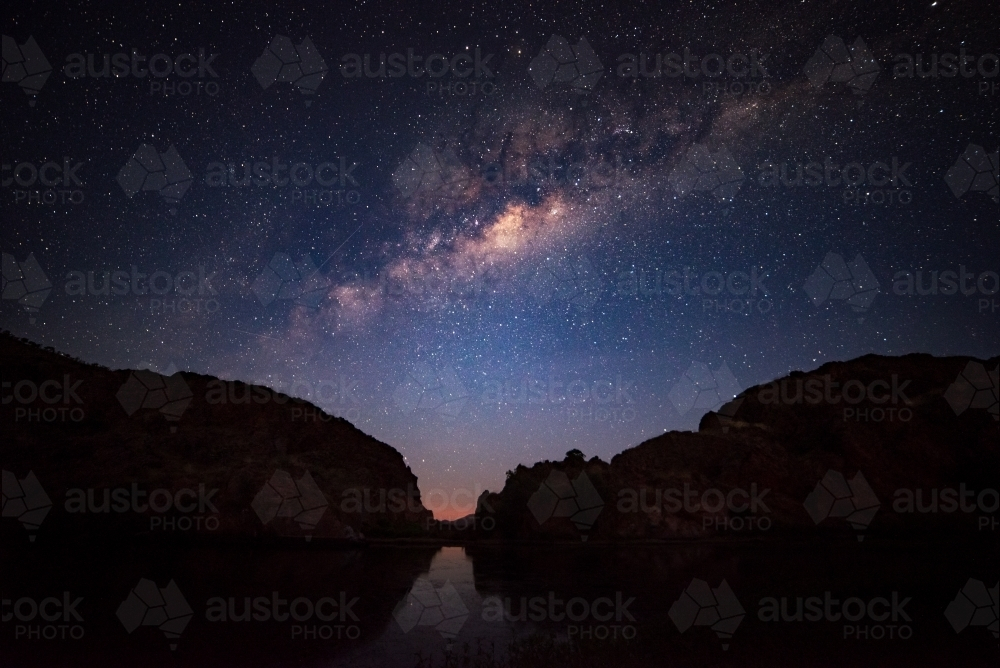 Silhouettes of two mountains under a night sky filled with stars. - Australian Stock Image