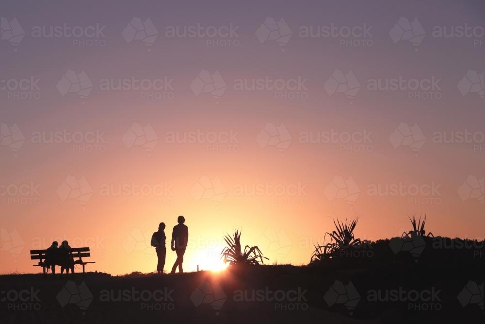 Silhouettes walking at sunset - Australian Stock Image