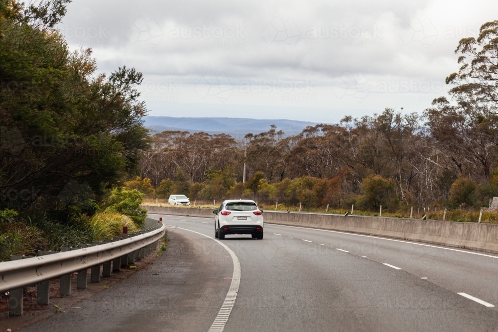 Single car driving around bend in highway road in western NSW - Australian Stock Image