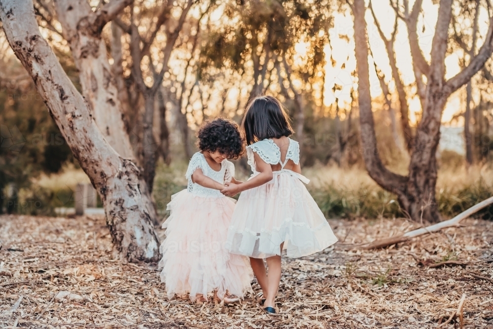 Sisters dancing at the park, young girls holding hands - Australian Stock Image