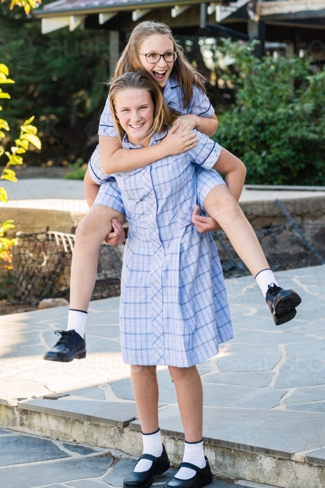 sisters mucking about in school uniform - Australian Stock Image