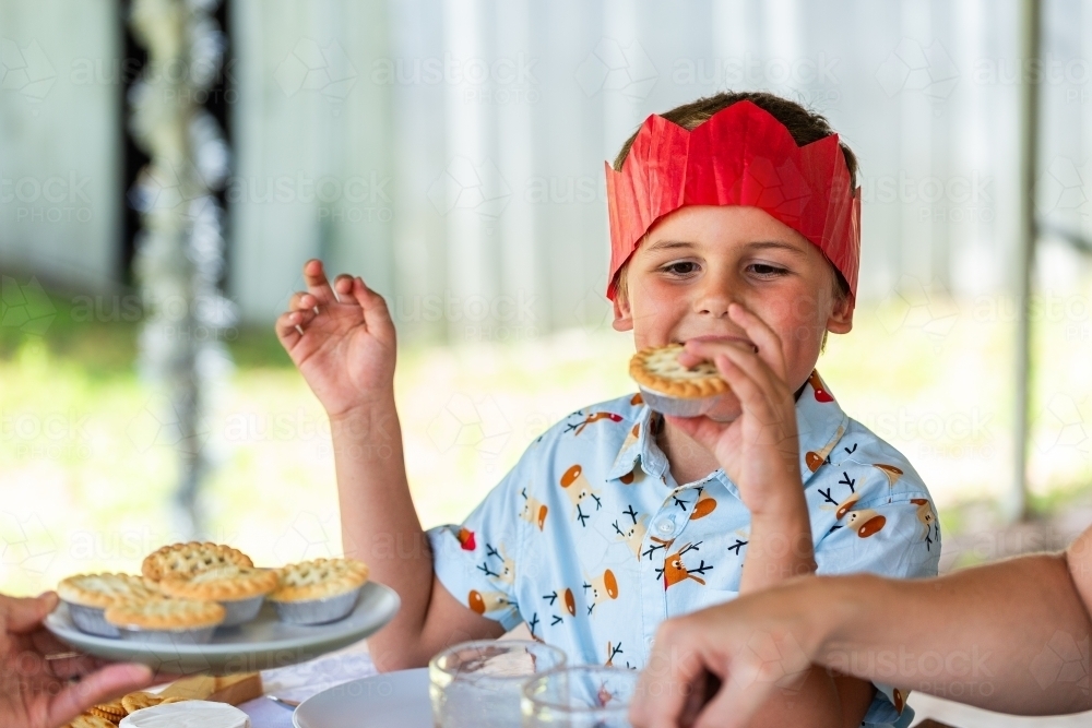 six year old Aussie kid eating fruit mince pie for dessert at Christmastime - Australian Stock Image