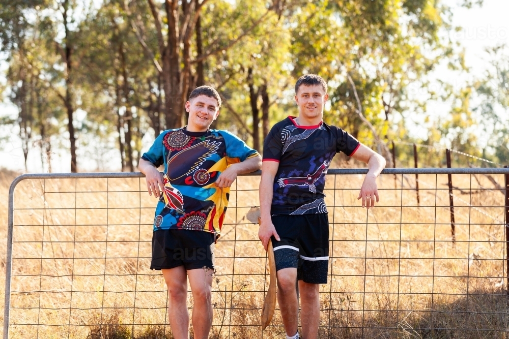 Sixteen year old Aboriginal cousins leaning on gate in country together - Australian Stock Image