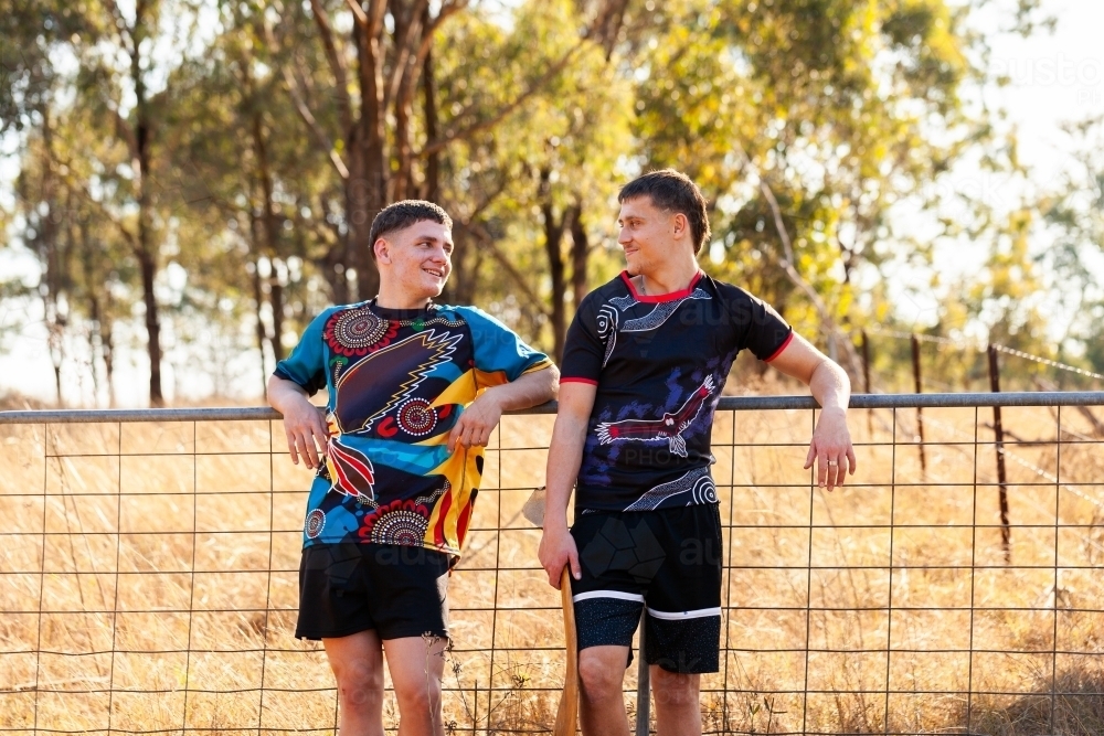 Sixteen year old Aboriginal cousins leaning on gate in country together - Australian Stock Image