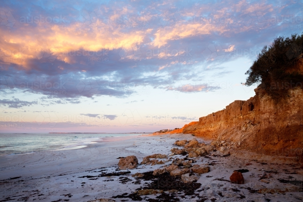 small cliffs along beach at sunrise - Australian Stock Image