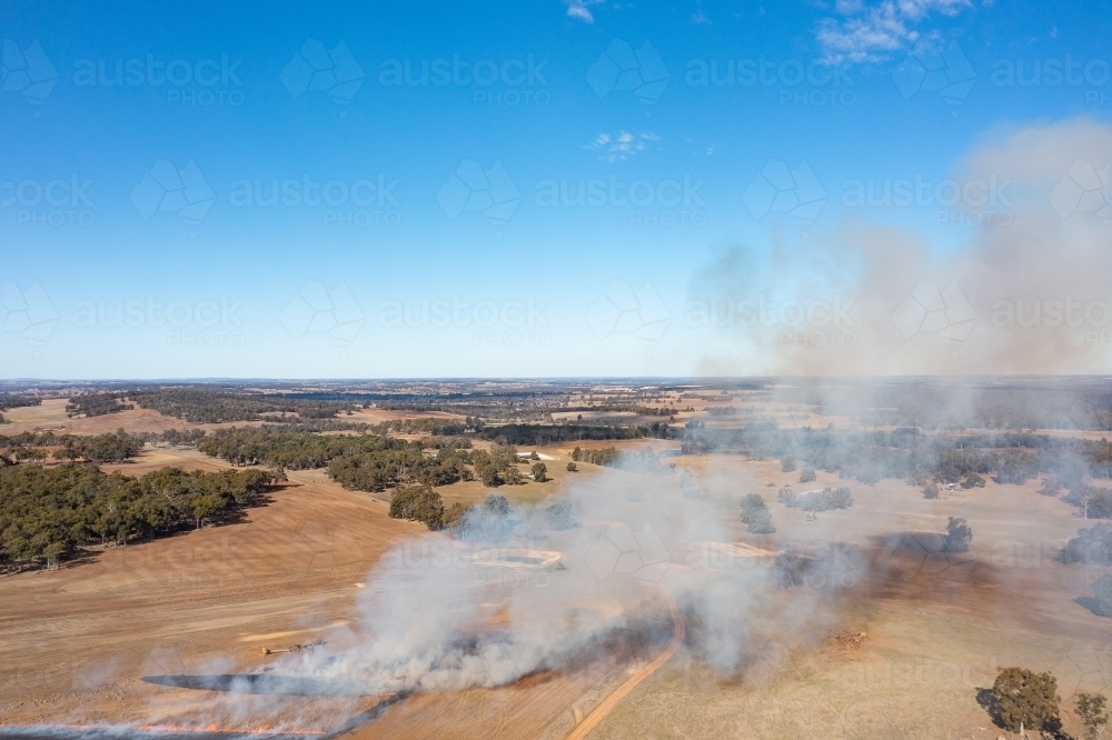 Small paddock fire with smoke drifting across dry landscape - Australian Stock Image