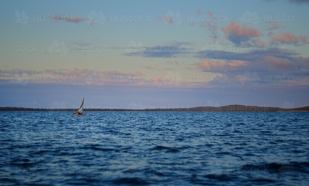 Small sailing boat in vast seascape between Bird Island and Turkey Beach, Queensland - Australian Stock Image