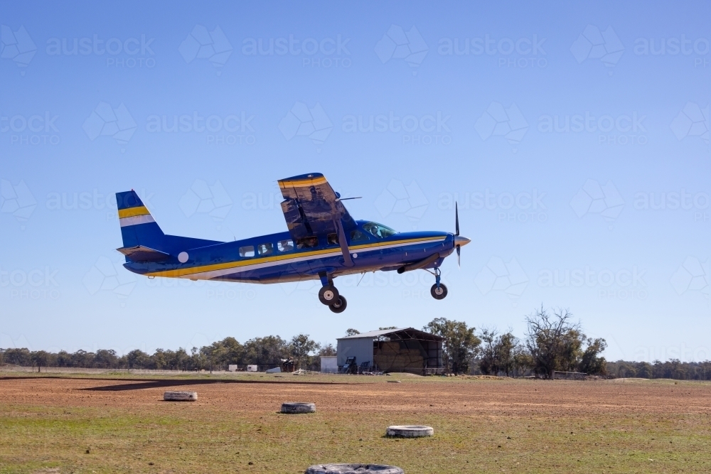 small single propeller aeroplane taking off a rural airstrip against blue sky - Australian Stock Image