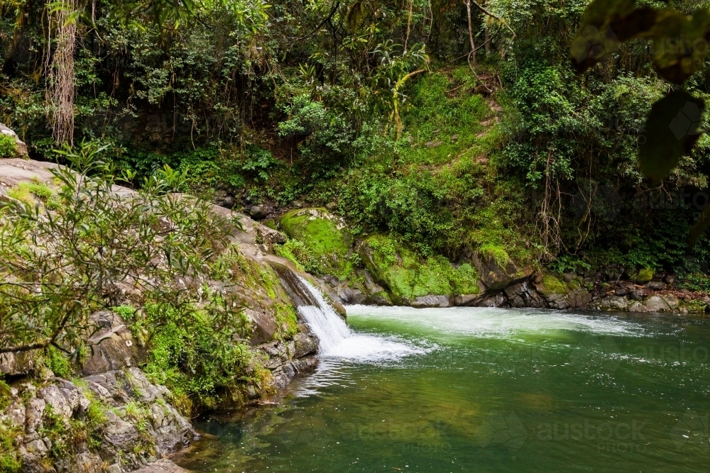 Small waterfall into tranquil green pool on Allyn River - Australian Stock Image