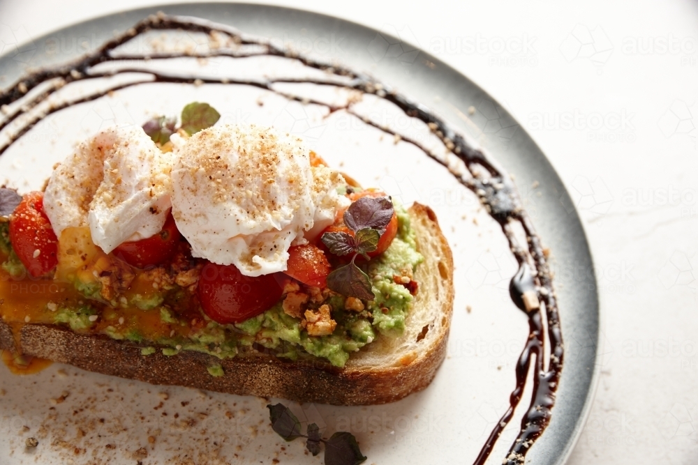 smashed avocado toast with tomato and poached eggs - Australian Stock Image