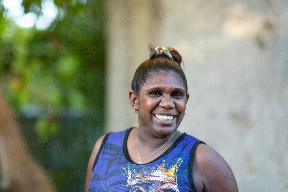 smilimg woman outside with hair in messy bun - Australian Stock Image