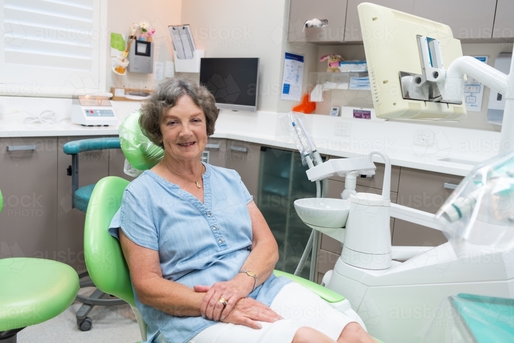 Smiling elderly female patient in dental chair - Australian Stock Image