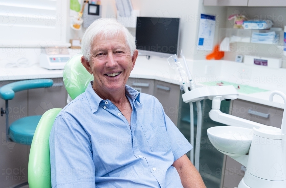 Smiling elderly male patient in dental chair - Australian Stock Image