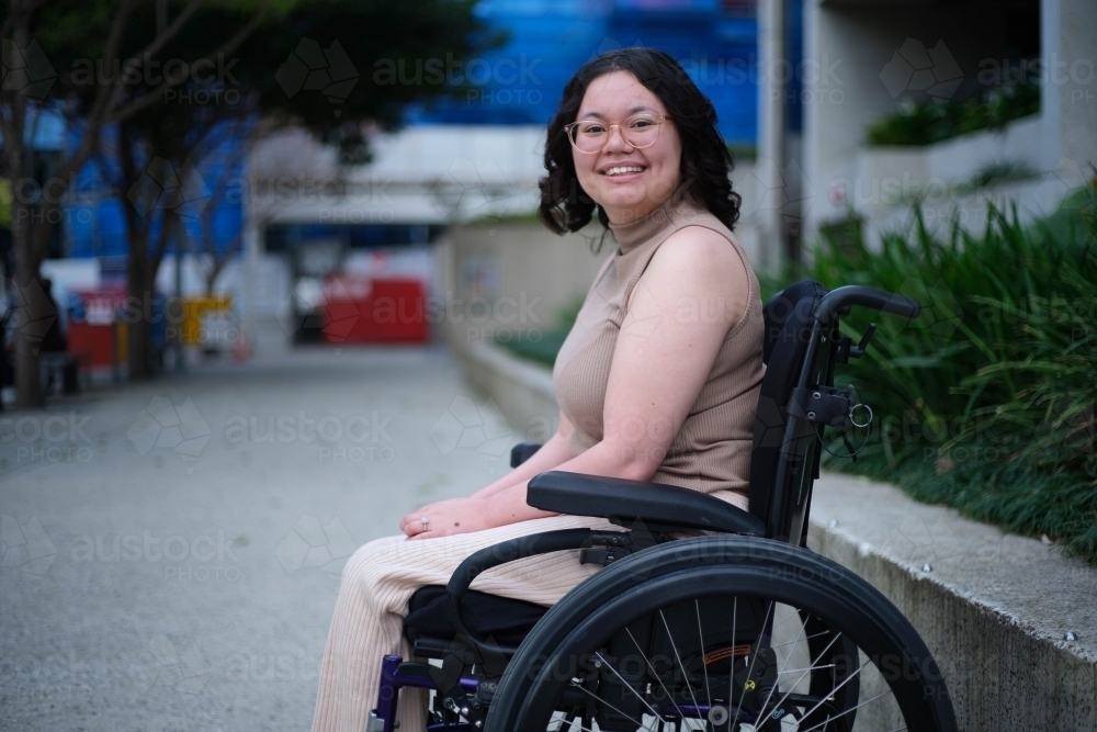 Smiling Filipina woman in wheelchair outside - Australian Stock Image