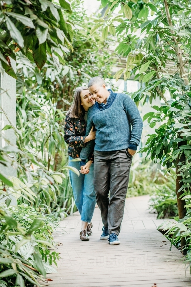 smiling lgbtqi couple holding hands and being cozy while walking in the garden - Australian Stock Image