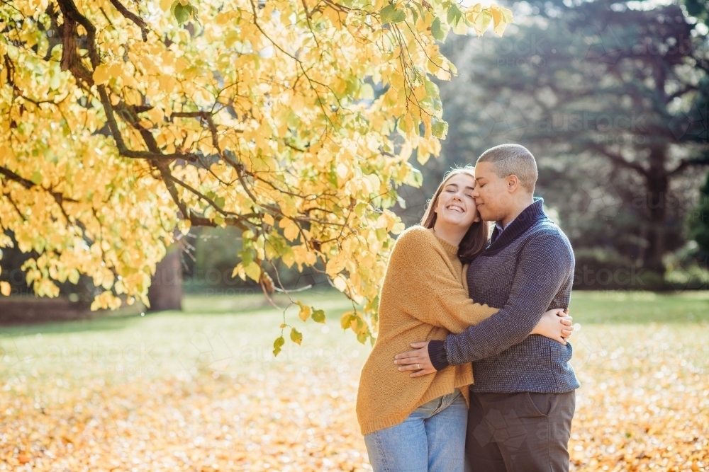 smiling lgbtqi couple hugging each other by autumn trees - Australian Stock Image