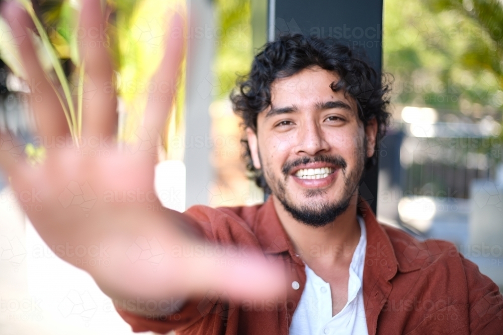 Smiling man reaching toward the camera outside - Australian Stock Image