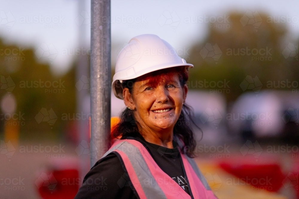 smiling mature woman outside wearing hi-vis vest and a hard hat - Australian Stock Image