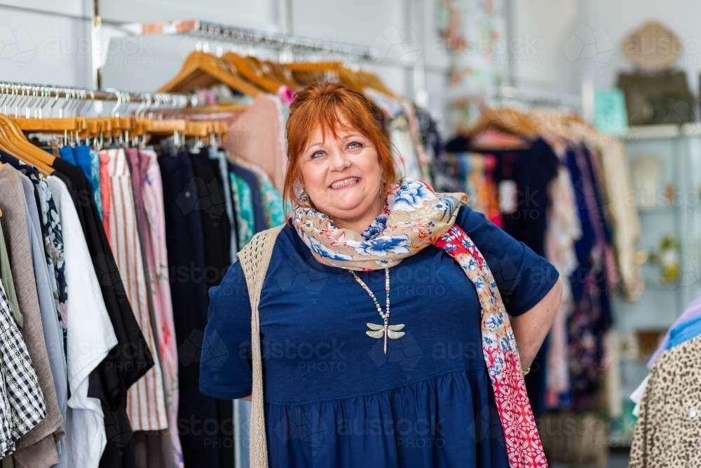 Smiling portrait of a happy middle aged woman in clothing boutique store - Australian Stock Image